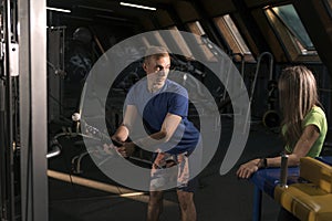 Fitness trainer conducts personal training in gym. Athletic guy shows exercise for triceps on simulator