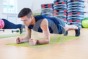 Fitness training athletic sporty man doing plank exercise in gym or yoga class exercising workout