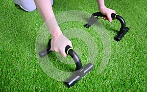 Fitness training with push up bars on the artificial grass