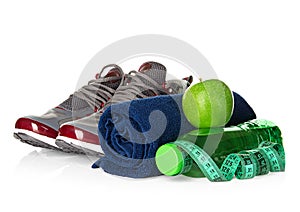 Fitness, weight loss concept with sneakers, green apples, bottle of drinking water and tape measure