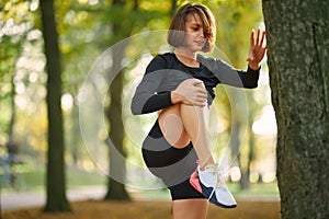 Fitness woman in activewear stretching legs on fresh air