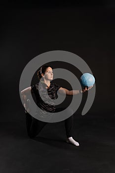 Fitness woman with Aqua ball, doing exercises. Goes in for sports on a black background looks at the camera