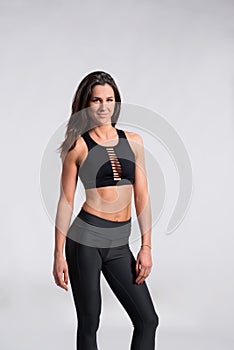 Fitness woman in black tank top and leggings, studio shot.