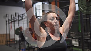 Fitness woman doing barbell thruster exercise in gym
