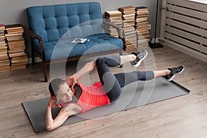 Fitness woman doing bicycle crunch exercise on mat at home