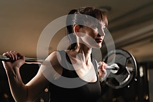 Fitness woman doing exercise with heavy weight bar in the gym. Female putting effort while exercising with heavy weights