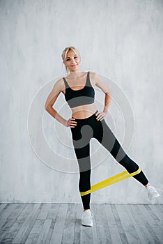 Fitness woman doing leg exercises with yellow fitness gum