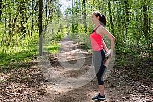 Fitness woman doing leg stretching before run in forest