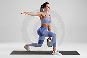 Fitness woman doing lunges exercises with kettlebell, leg muscle training. Active girl doing front forward one leg step lunge