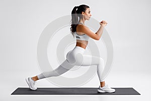 Fitness woman doing lunges exercises for leg muscle training. Active girl doing front forward one leg step lunge exercise