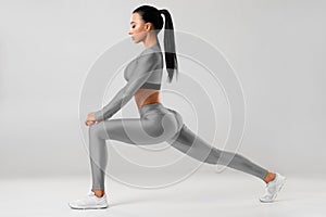 Fitness woman doing lunges exercises for leg muscle training. Active girl doing front forward one leg step lunge exercise