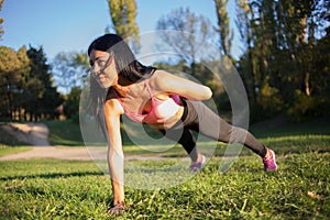 Fitness woman doing plank core exercise workout on grass