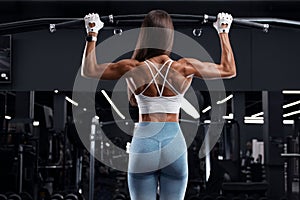 Fitness woman doing pull-ups exercise for back muscles, working out in gym . Athletic girl training