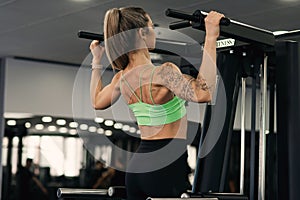 Fitness woman doing pull-ups exercise for back muscles, working out in gym . Athletic girl training