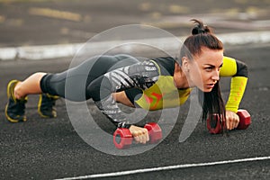 Fitness woman doing push-ups in the stadium, cross training workout. Sporty girl training outside