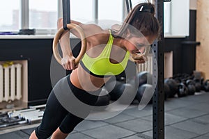 Fitness woman doing push ups training arms with gymnastics rings in the gym Concept workout healthy lifestyle sport.