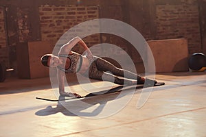 Fitness woman doing side plank exercise workout in gym indoors