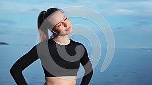 Fitness woman doing warm up exercise with closed eyes at seascape. Medium shot on RED camera