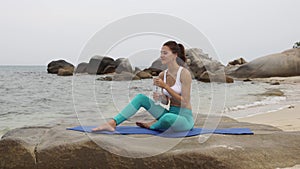 Fitness woman drink water after doing sport exercises on beach at sunset.