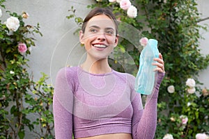 Fitness woman drinking water from bottle outdoor. Thirsty woman holding glass drinks still water preventing dehydration