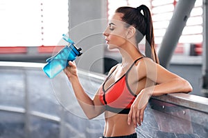 Fitness woman drinking water from a bottle. Young active girl quenches thirst photo