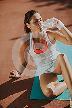 Fitness woman drinking water after running