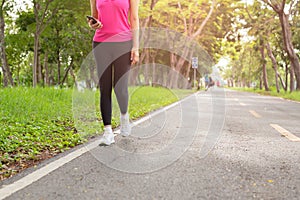 Fitness woman exercise walking on park trail with hand holding cell phone.