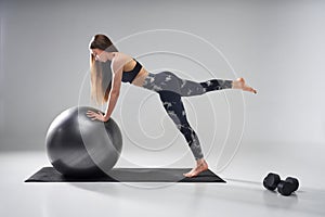 Fitness woman exercising on grey pilates ball.