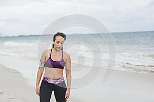 Fitness Woman finishing work out by the Ocean at cloudy winter day