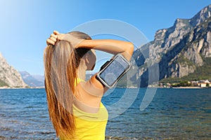 Fitness woman fixing hair outdoor in her daily workout she use sport arm band for smart phone