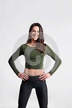 Fitness woman in green t-shirt and sports leggings, studio shot.