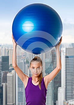 Fitness woman holding exercise ball during workout. Beautiful smiling happy caucasian fit female fitness woman over city