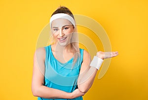 Fitness woman holding free advertising space for your product on her palm, copy space. Isolated on white. Half length of