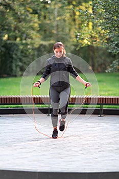 Fitness woman jumping on a rope outdoor in urban environment