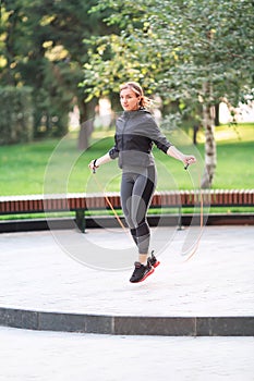 Fitness woman jumping on a rope outdoor in urban environment