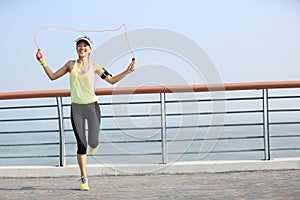 Fitness woman jumping rope at seaside