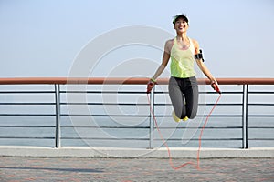 Fitness woman jumping rope at seaside