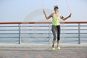 Fitness woman jumping rope at seaside