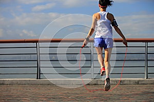Fitness woman jumping rope at seaside