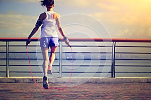 Fitness woman jumping rope at seaside