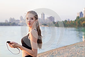 Fitness woman at lake listening to music on mobile phone