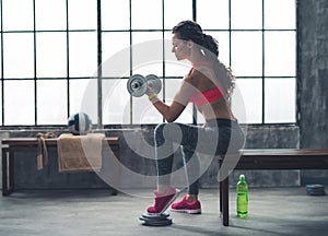 Fitness woman lifting dumbbell in urban loft gym