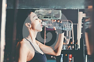 Fitness woman in loft gym drinking water After a good workout