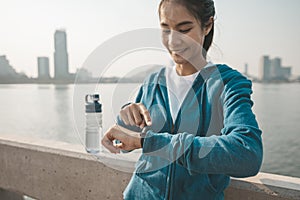 Fitness woman looking and checking at her smart watch while taking a break from running. Sport with smart divice concept