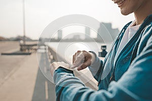 Fitness woman looking and checking at her smart watch while taking a break from running. Sport with smart divice concept