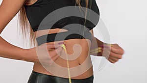 Fitness woman measuring her waist with tape measure isolated