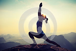 Fitness woman meditating on sunrise mountain peak