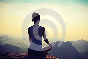 Fitness woman meditating on sunrise mountain peak