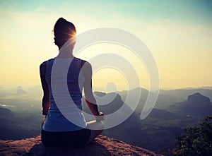 Fitness woman meditating on sunrise mountain peak