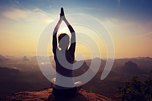 Fitness woman meditating on sunrise mountain peak